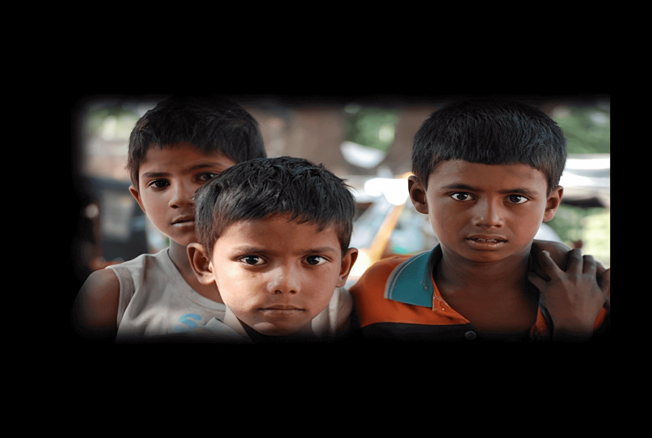 Three boys standing close together outdoors.